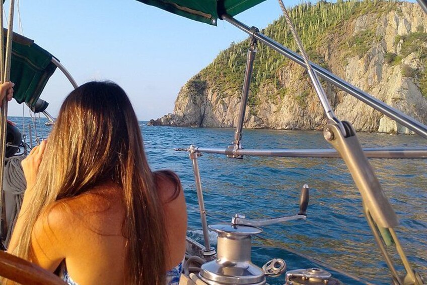 A person on a boat, water, and rocky coastline. 5