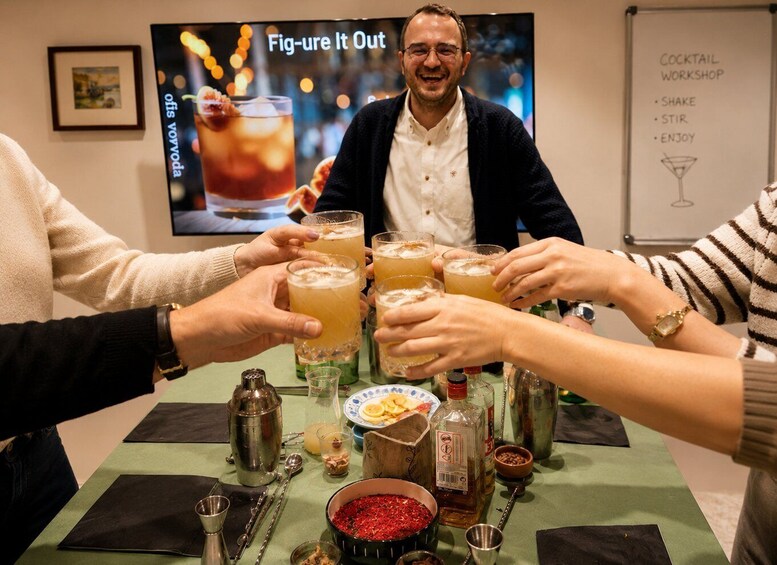 Un grupo de personas brindando con bebidas en un taller de coctelería. 5