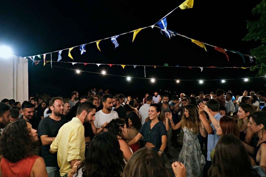 A crowded outdoor event with people dancing and a string of colorful flags overhead. 3
