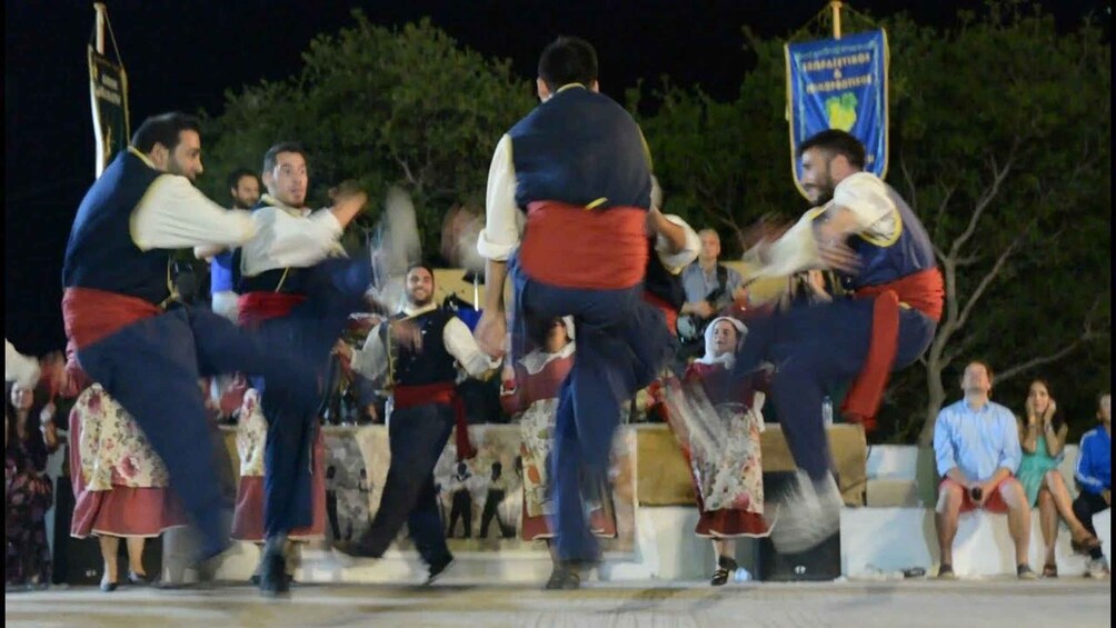 A nighttime outdoor event with people in traditional attire performing a dance. 4
