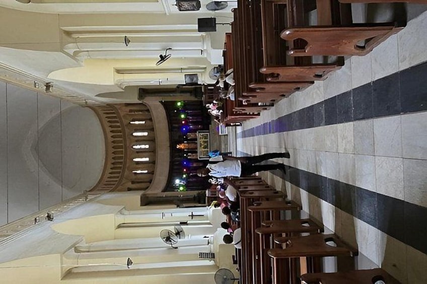 An interior of a church with rows of pews, a central altar, and a dome-shaped ceiling. 3