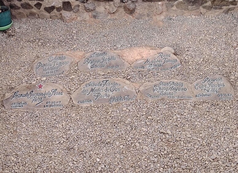 A series of engraved stones with names and dates on a gravel surface. 5