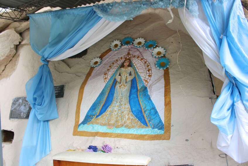 A religious mural with a figure in blue and gold attire, surrounded by blue and white drapery. 2