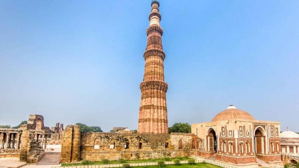 A tall minaret with a dome, surrounded by ancient ruins and a mosque. 5