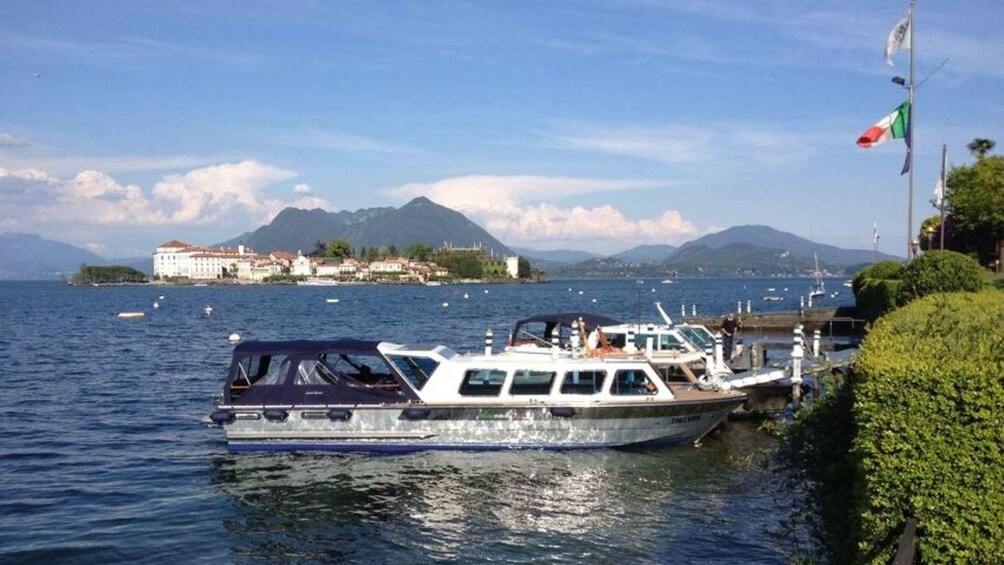 A boat docked near a waterfront with a mountainous backdrop and a building on an island. 3