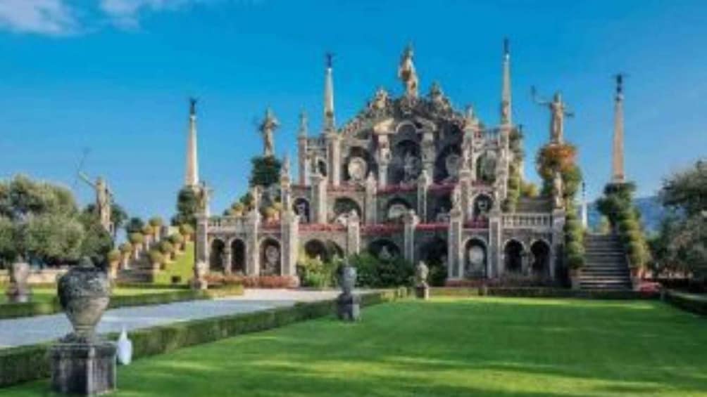 A grand, ornate building with multiple spires and arches, surrounded by well-manicured lawns and trees. 2
