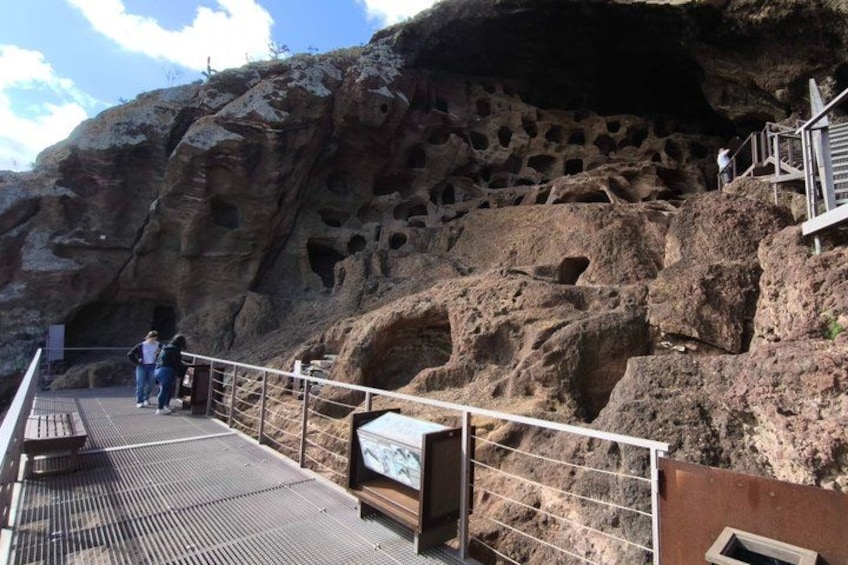 A rocky cliff with numerous caves and a viewing platform with railings. 2