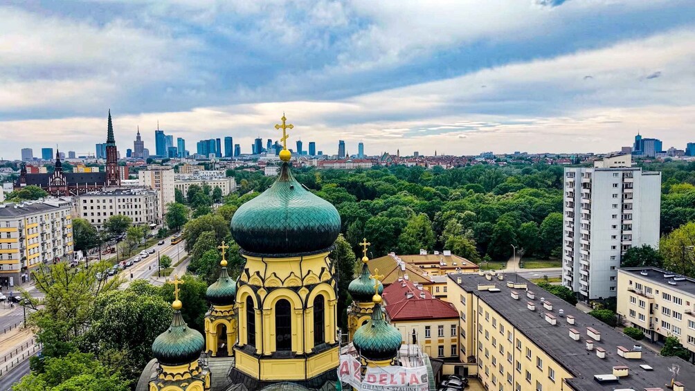 A cityscape with a prominent yellow and green church with multiple domes, surrounded by urban buildings and a dense green park. 2