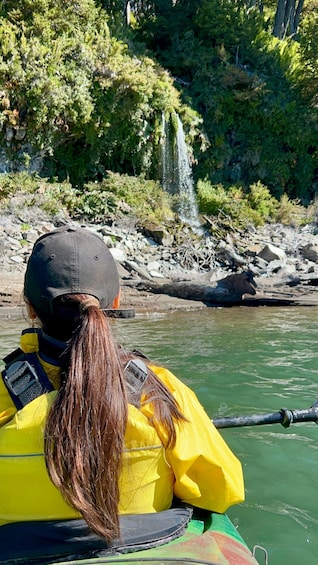 A person kayaking on a river with a waterfall in the background. 2