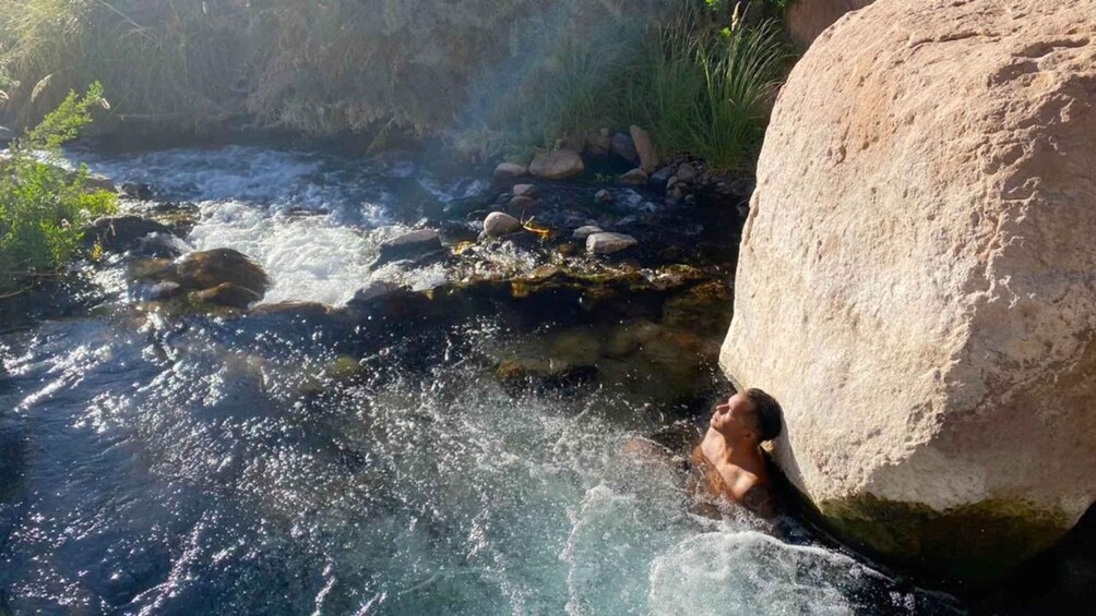 A person swimming in a river with rocks and greenery around. 2