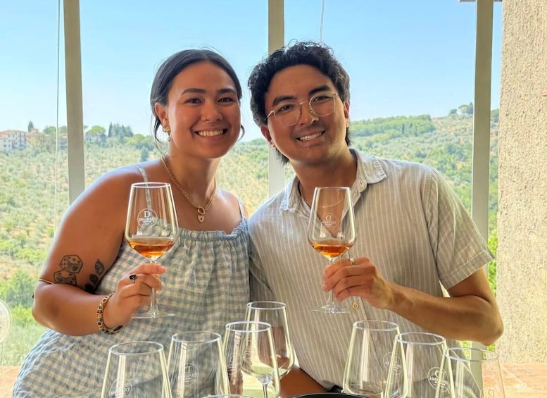 Two people sitting at a table with wine glasses, overlooking a scenic landscape. 1