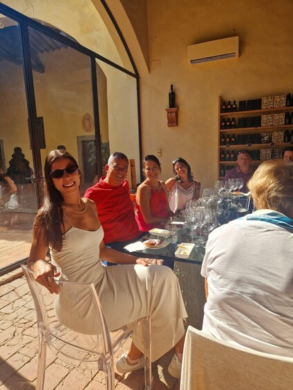 A group of people dining outdoors at a restaurant with a wine rack in the background. 1