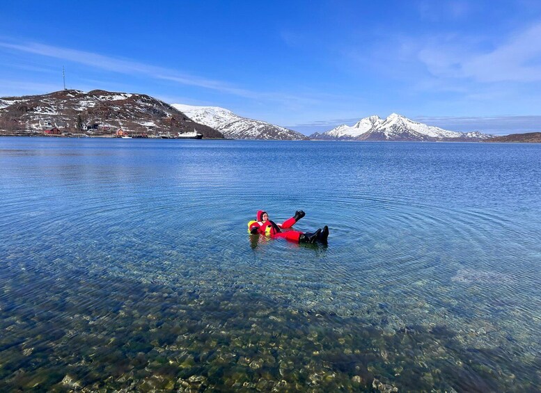 A person floating on a clear lake with mountains in the background. 2