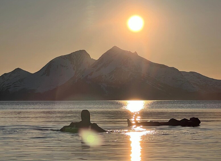 A person floating on water with mountains in the background during sunset. 3