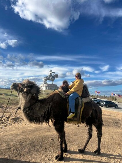 A person riding a camel with a statue in the background. 3