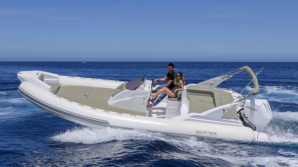 A white motorboat with two people on board, moving on a calm sea. 2