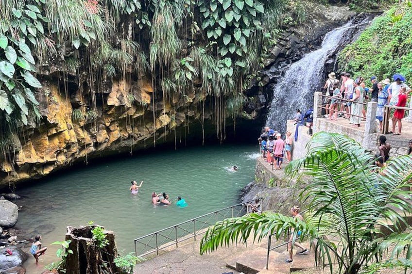 A waterfall, a swimming area, and people enjoying the water. 1