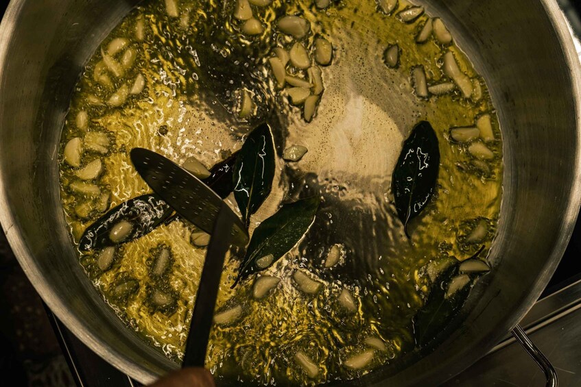 A pot with garlic cloves and bay leaves simmering in oil. 2