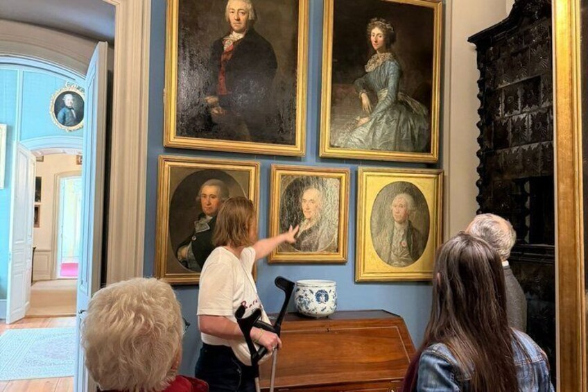 A room with portraits on the wall, a wooden cabinet, and a blue door. 3