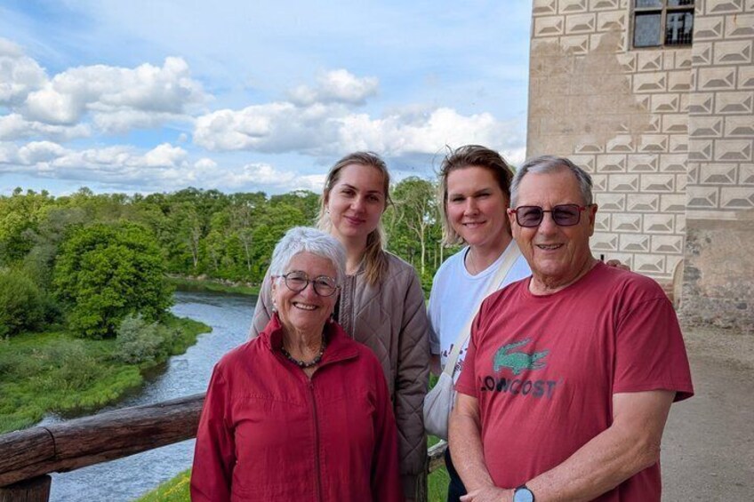 A group of people standing by a river with a building in the background. 1