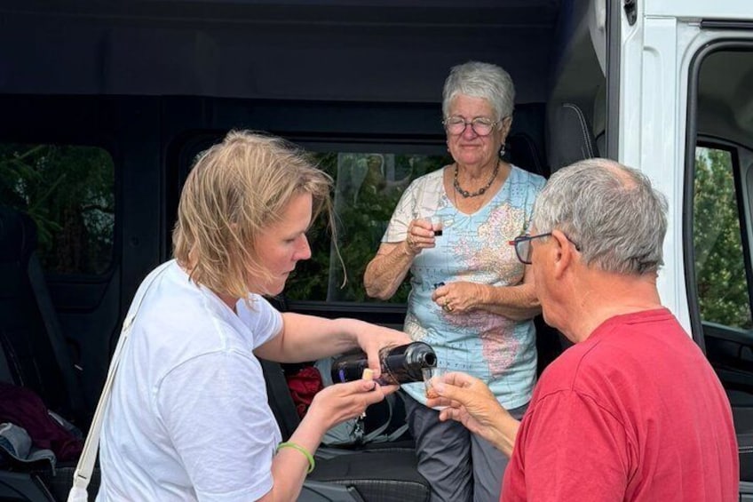 Three people interacting near a vehicle with a camera. 2