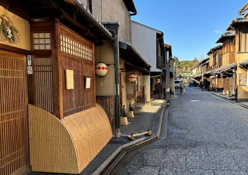 A narrow street lined with traditional wooden buildings, some with tatami mats and sliding doors. 3