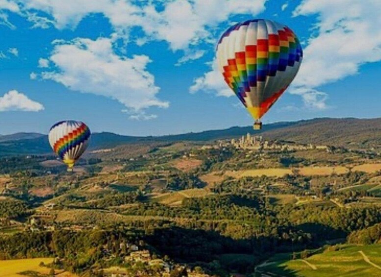 Two hot air balloons over a hilly landscape with a town in the background. 5