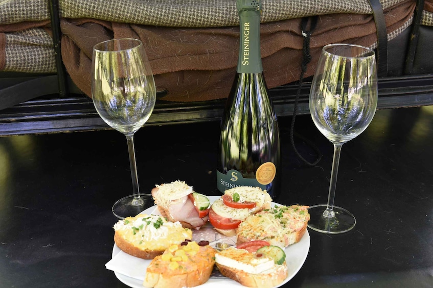 A bottle of Steiniger wine, two glasses, and a plate of assorted sandwiches. 2