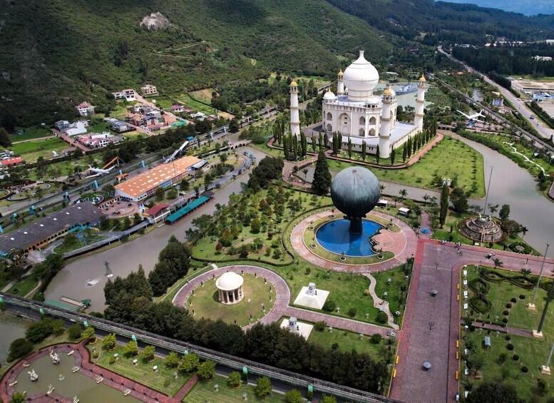 A large white building with domes, a roundabout, a fountain, and a river. 1