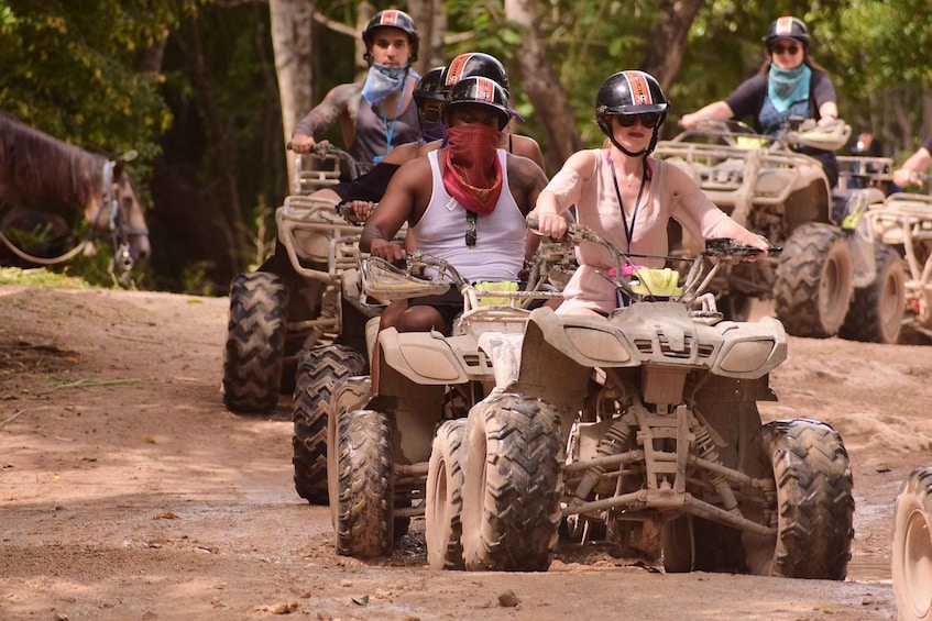 People riding ATVs on a dirt path surrounded by trees. 5