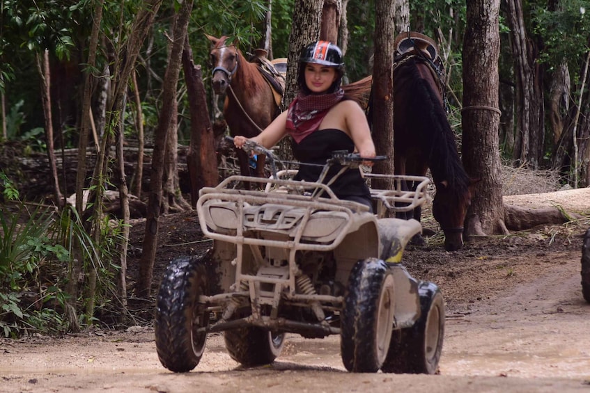 A person riding an ATV in a forested area with a horse in the background. 4