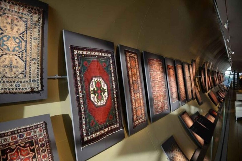 A museum exhibit with various traditional rugs displayed on walls. 4