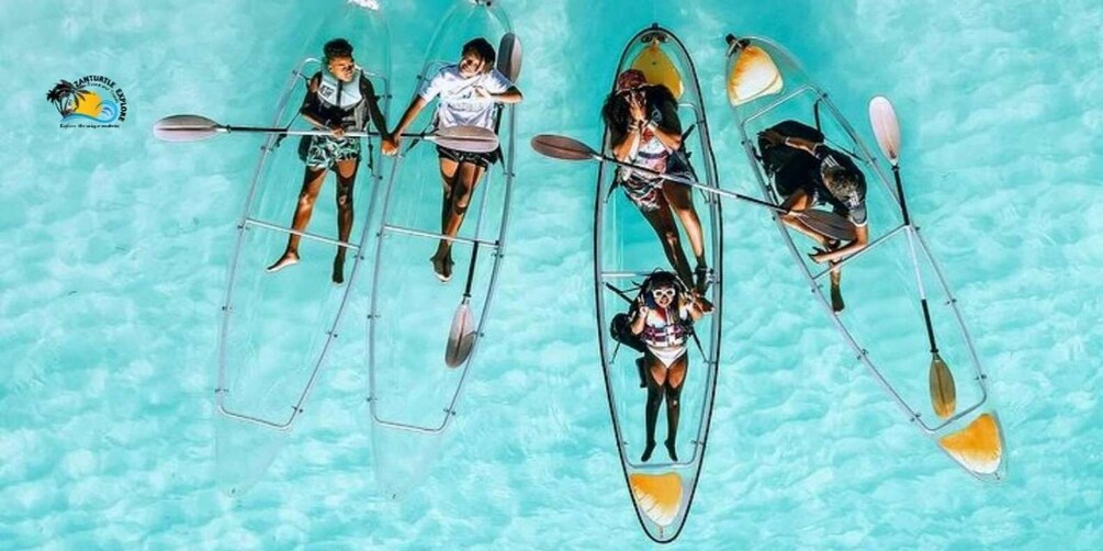 Four people in kayaks on a turquoise pool. 4