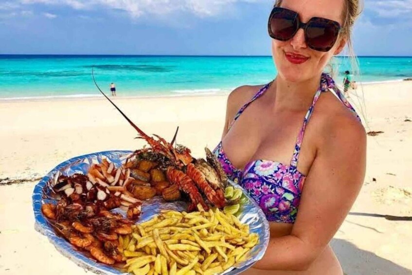 Una donna tiene un piatto di frutti di mare e patatine fritte su una spiaggia. 1