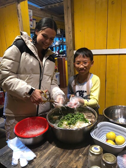 Une personne prépare des aliments à l’aide d’un saladier rempli d’ingrédients, d’une passoire rouge et d’un bol en métal, le tout posé sur une table en bois. 2