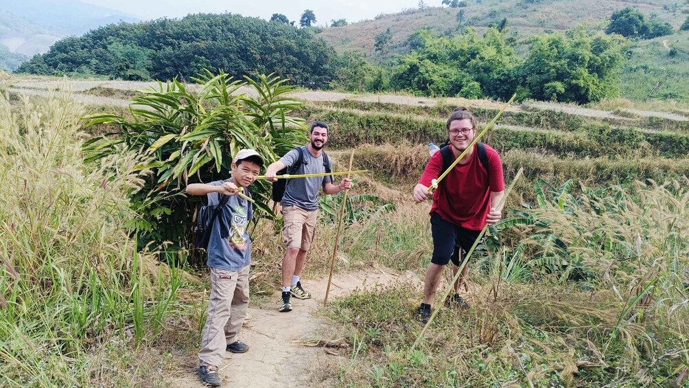 Three people hiking on a dirt path surrounded by lush greenery and hills. 5
