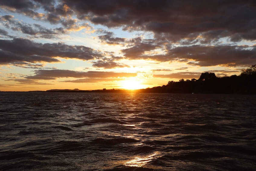 A sunset over a body of water with clouds reflecting the sunlight. 1