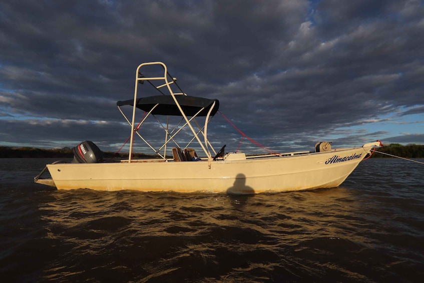 A boat named "Almacatima" on calm water with a cloudy sky in the background. 3