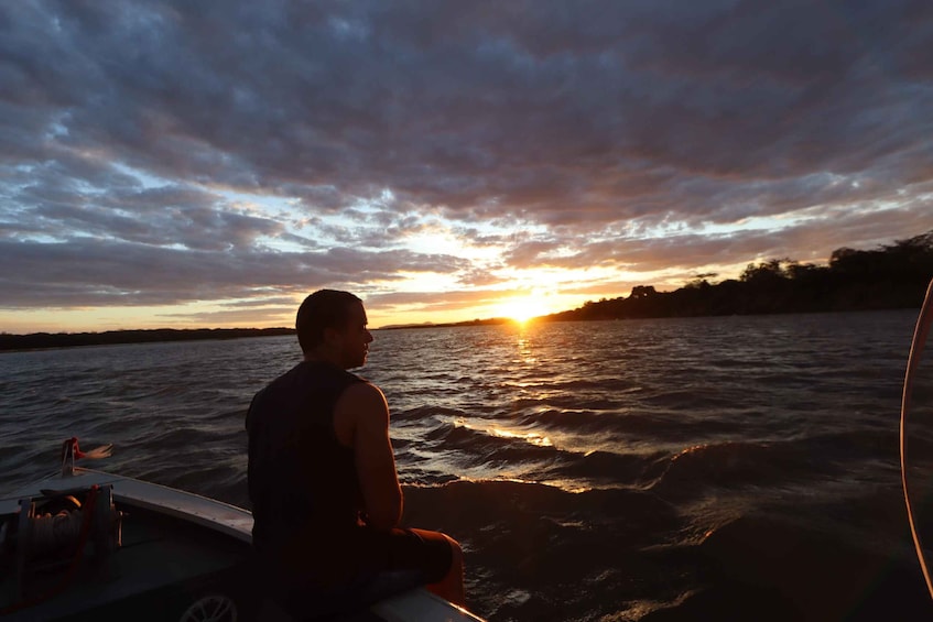 A person sitting on a boat during sunset. 5