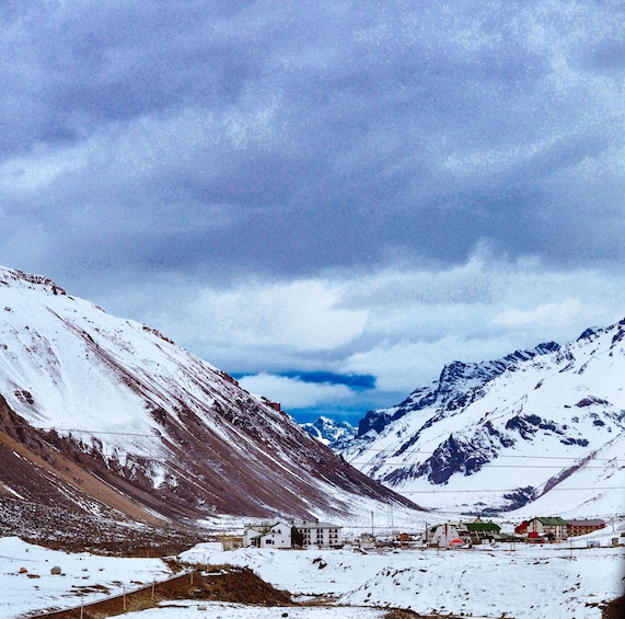 A snow-covered mountainous landscape with a small settlement and a clear sky. 3