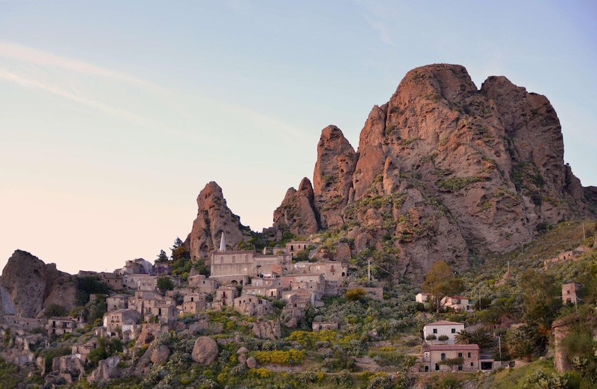 A rugged mountain with a village nestled at its base, featuring traditional stone buildings and rocky terrain. 1