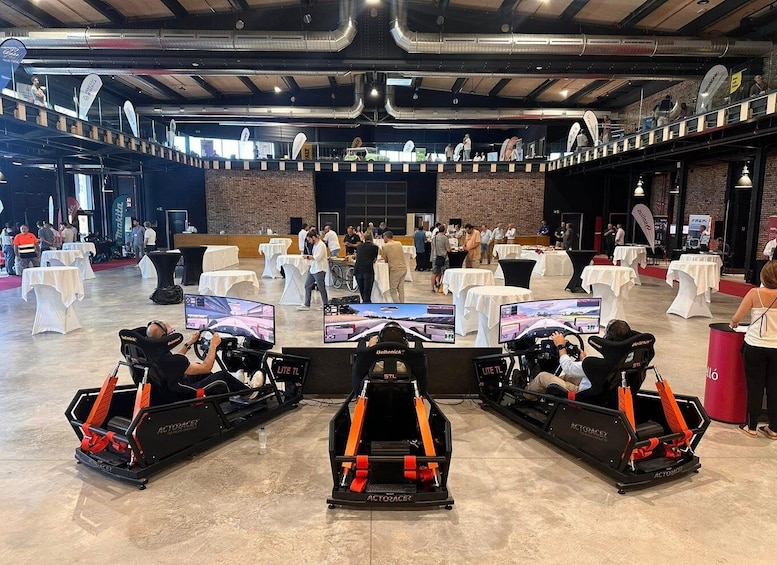 A racing simulator setup with three chairs and a central screen in a spacious indoor venue. 2