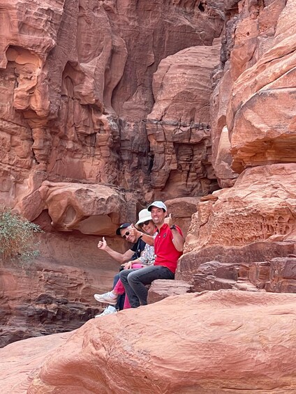 Two people sitting on a rock formation with a canyon in the background. 4