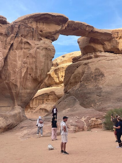 A natural rock arch formation with people standing and taking photos. 2