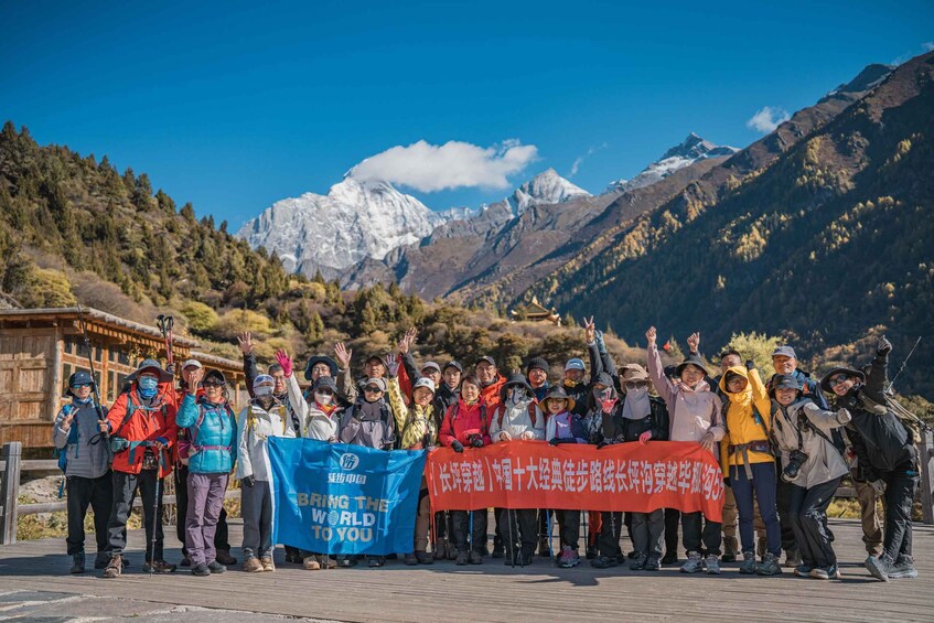 A group of people standing on a wooden platform with a mountainous backdrop. 1