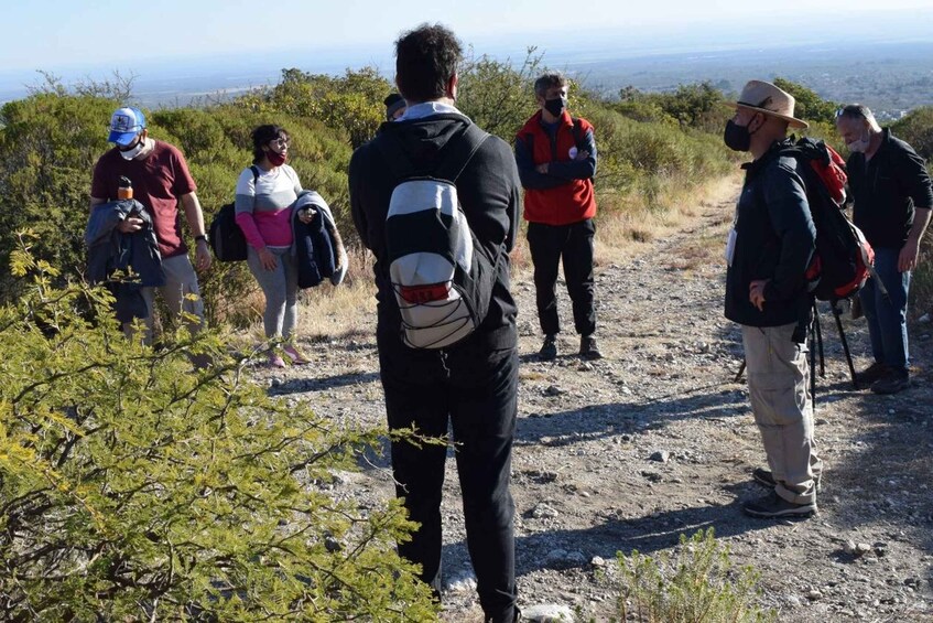 A group of hikers on a rocky trail with sparse vegetation and a distant view of the landscape. 2