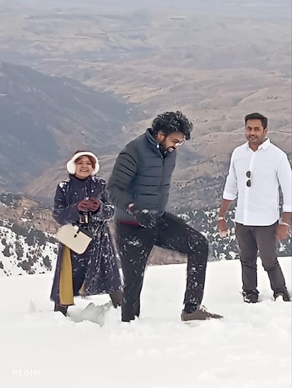 Three people in a snowy mountainous area, one holding a shovel. 5