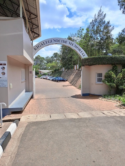 En minnesplats med en entré och en skylt med texten: "KIGALI-MINNESMÄRKET ÖVER FOLKMORDET". 1