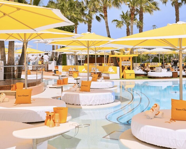 A poolside area with yellow umbrellas, lounge chairs, and palm trees. 5