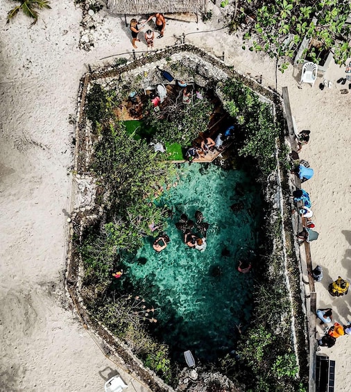 A circular pool surrounded by a concrete wall, with people swimming and sunbathing. 4